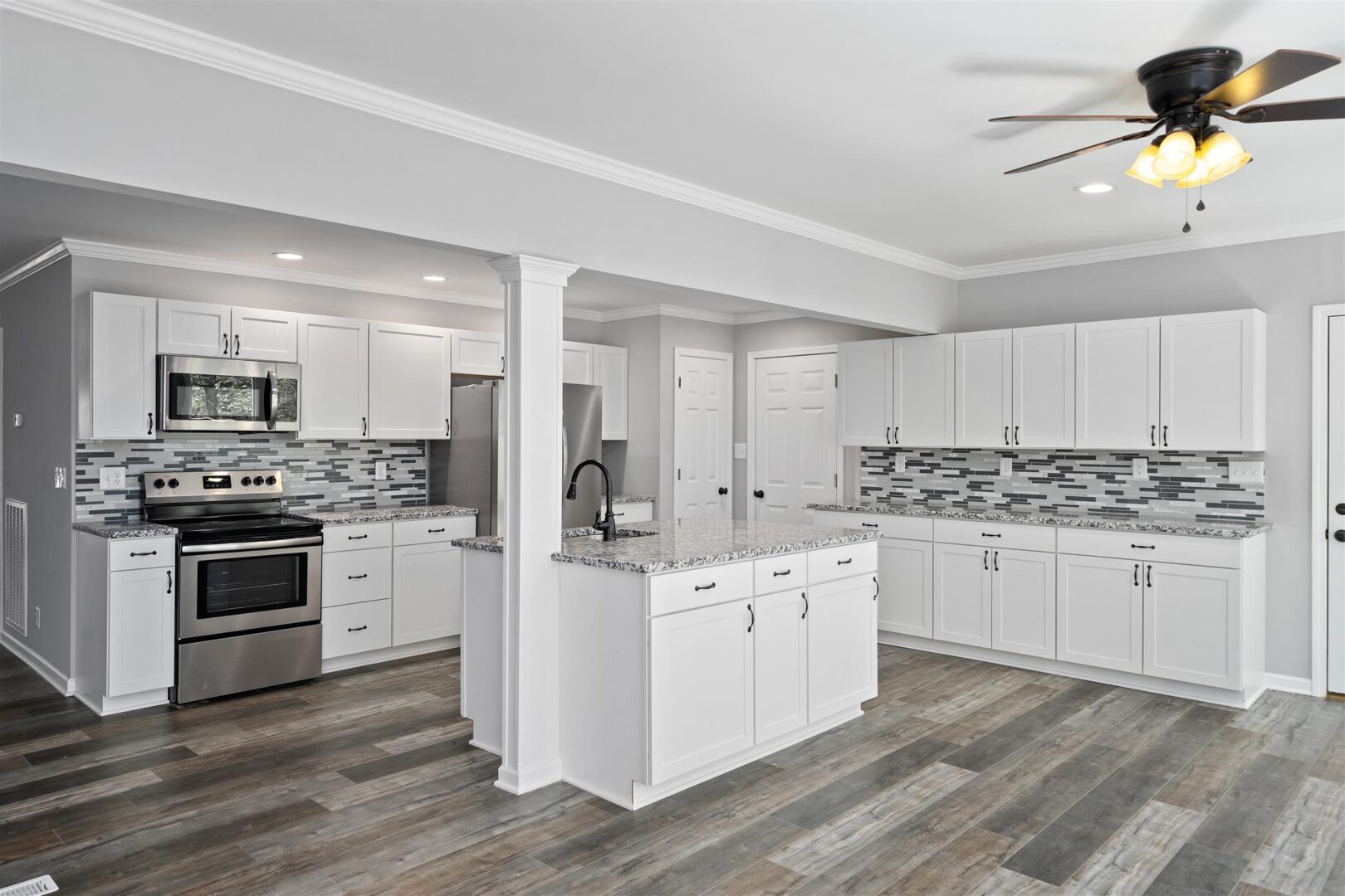 A kitchen with white cabinets and wood floors.